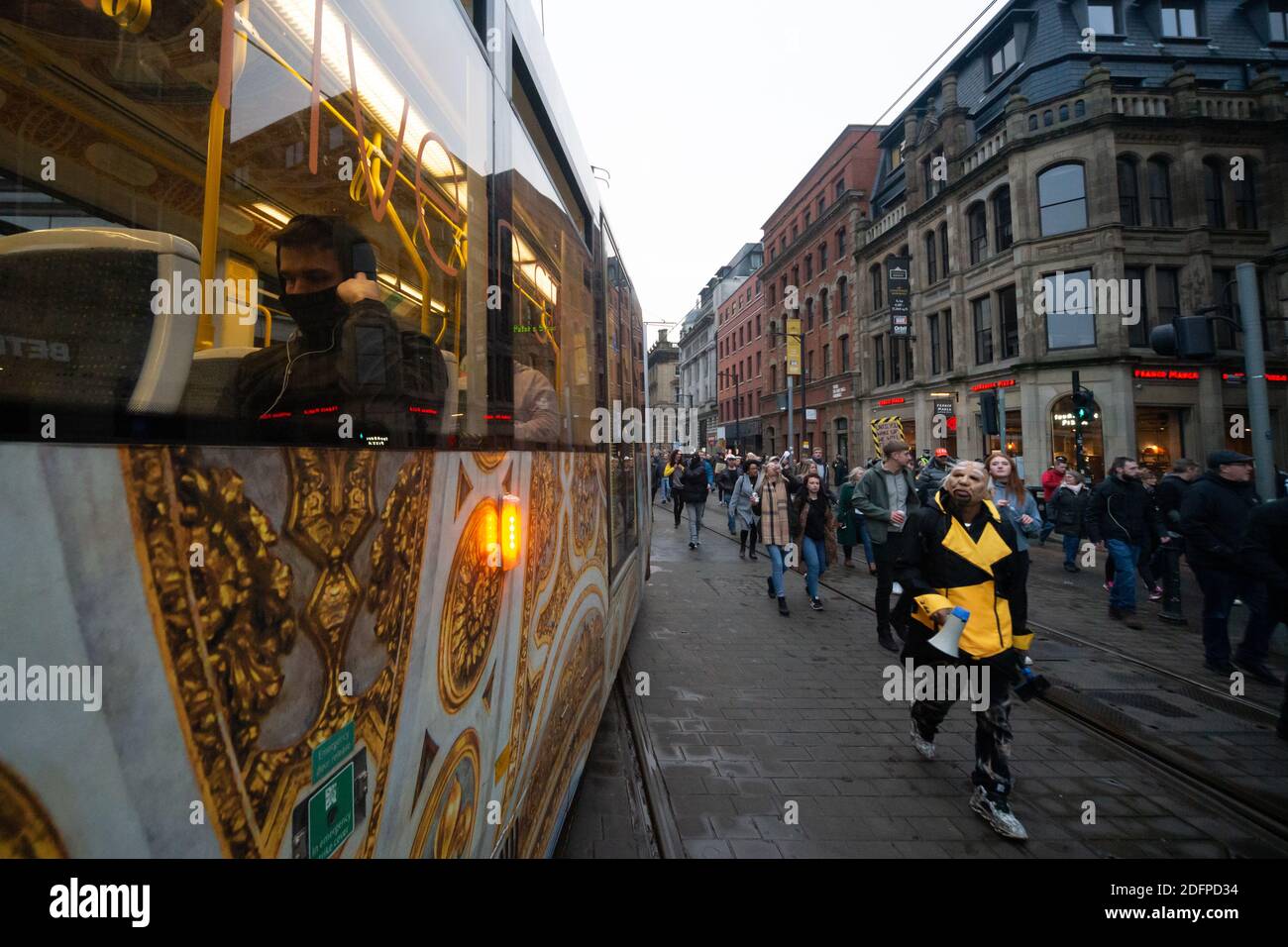 Manchester, Angleterre, Royaume-Uni. 6 décembre 2020. Une personne à l'intérieur d'un tramway portant une couverture faciale pendant que les manifestants passent en marche contre le coronavirus britannique et les mesures de niveau près de Piccadilly Gardens. Crédit : Callum Fraser/Alay Live News Banque D'Images