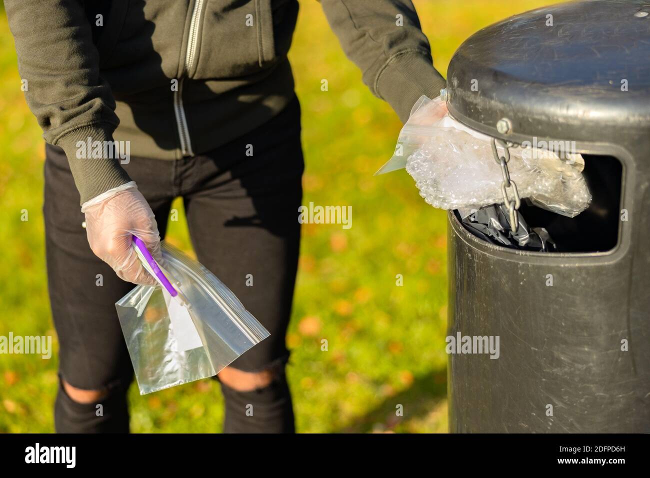 Mettez les déchets de plastique dans la poubelle du parc Banque D'Images