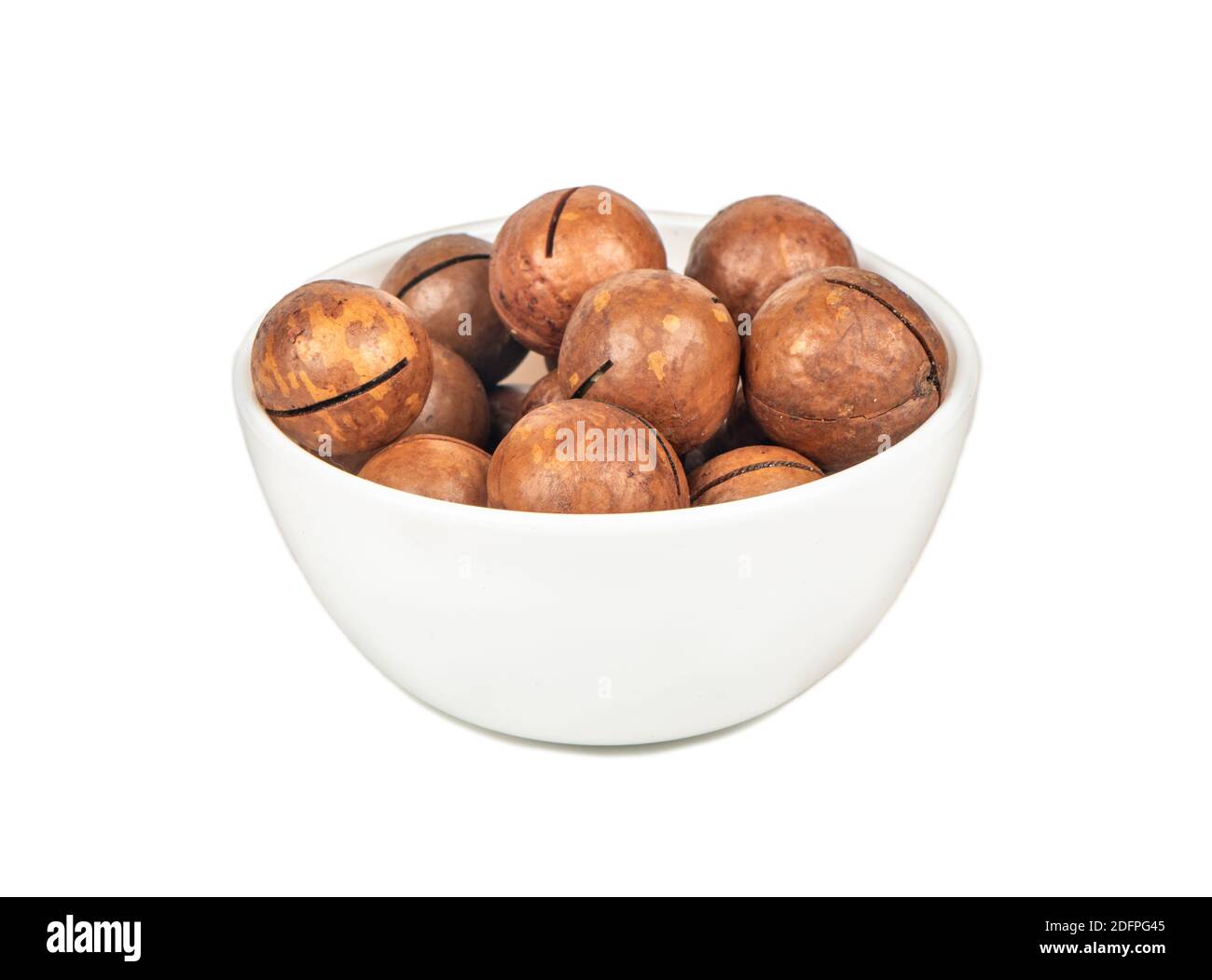Noix de macadamia dans un bol en céramique sur fond blanc Banque D'Images