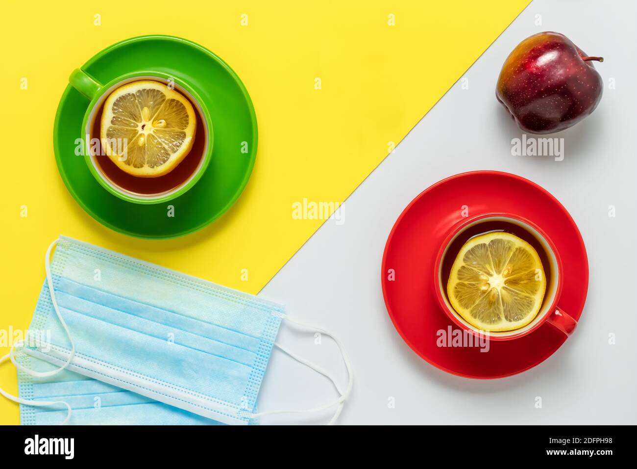 Thé avec des tranches de citron le matin. Thé pour deux et fruits aux pommes. Deux masques de protection sur la table dans le café. Deux tasses avec rouge et gre Banque D'Images