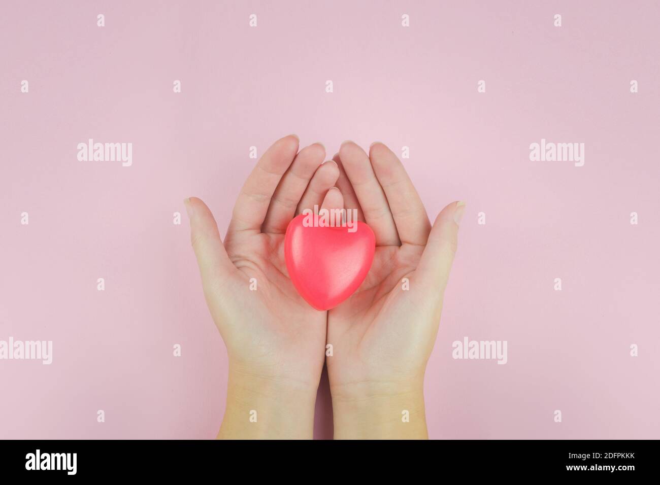 Femme tenant la forme du coeur sur le fond rose, les soins de santé, don et concept d'assurance familiale, Journée mondiale de la santé, concept de la Saint-Valentin Banque D'Images