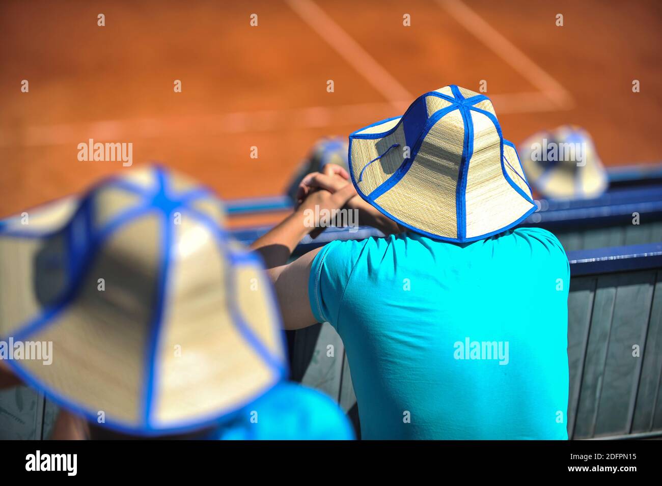 L'homme porte un chapeau de paille pour regarder un match de tennis pendant  une journée ensoleillée et chaude d'été Photo Stock - Alamy