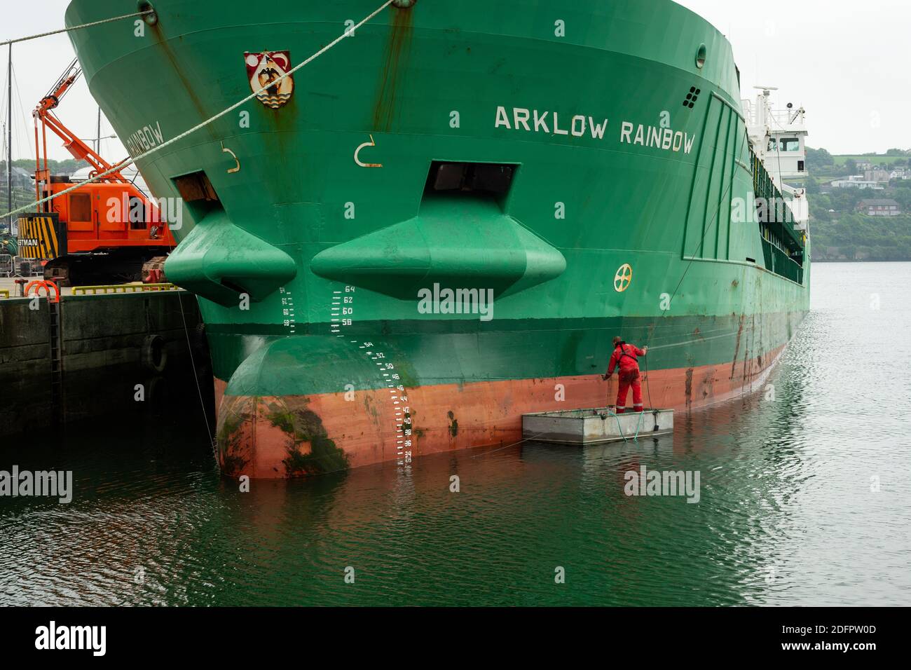 Le navire de cargaison Arklow Rainbow est peint en vert par un dyer mâle ou un peintre peint avec une petite brosse dans le port de Kinsale, en Irlande Banque D'Images