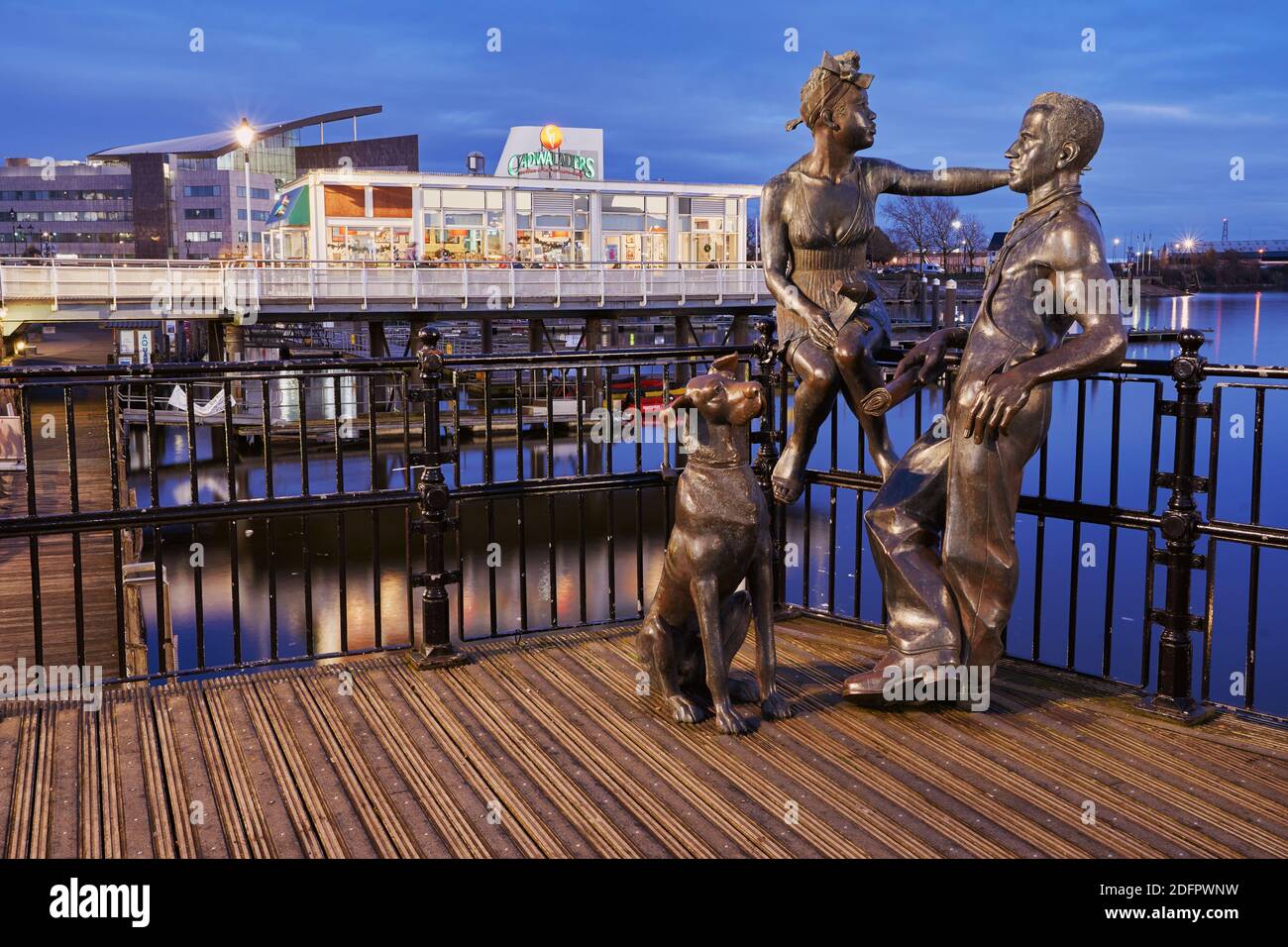 Les gens comme nous sculptaient sur le quai Mermaid dans la baie de Cardiff, au début de la soirée de décembre. La sculpture représente un couple immigré typique. Banque D'Images