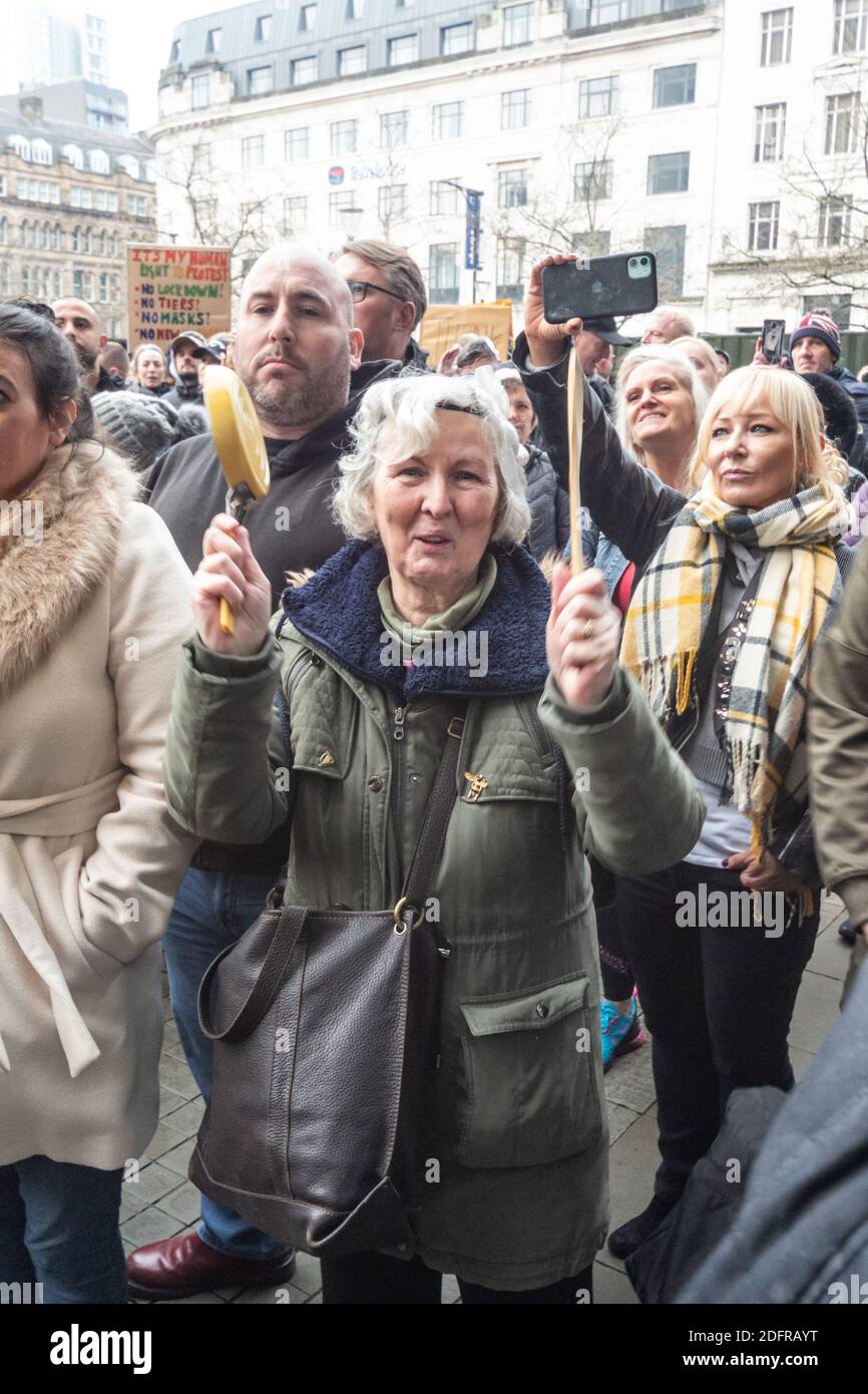 Manchester Piccadilly Gardens 6 décembre 2020 : une dame aux cheveux gris bat un petit pot avec une cuillère en bois pour soutenir les discours anti-verrouillage Banque D'Images