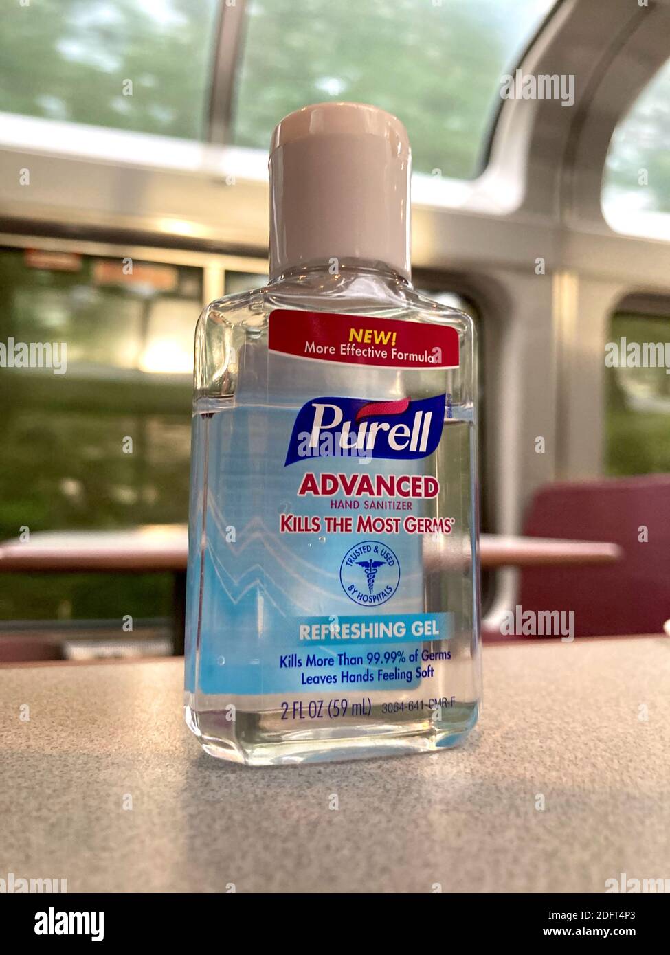 Gros plan d'une petite bouteille de désinfectant pour les mains de marque Purell laissée sur une table dans le salon d'un train Amtrak. Banque D'Images