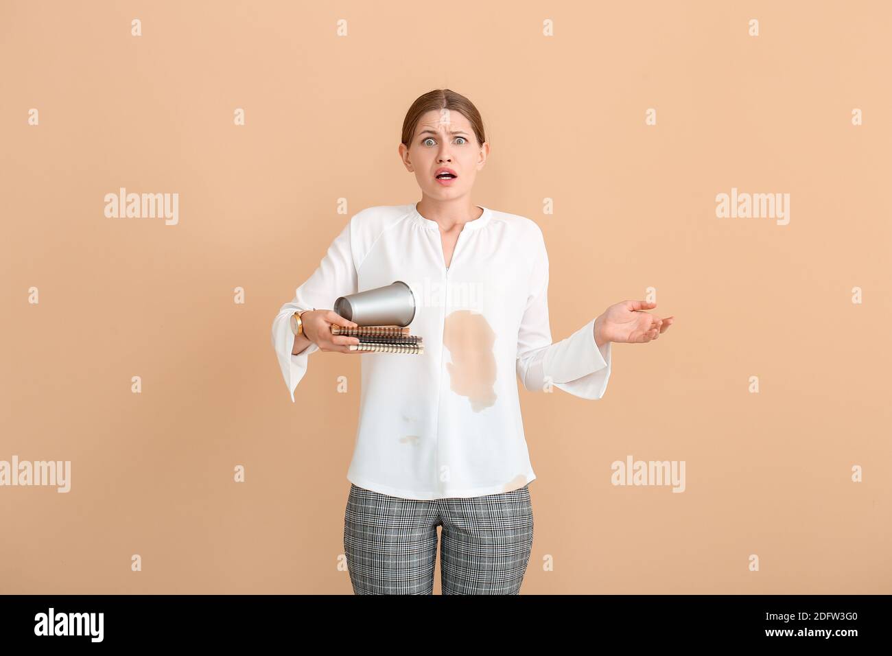 Jeune femme stressée avec taches de café sur sa chemise couleur de fond Banque D'Images