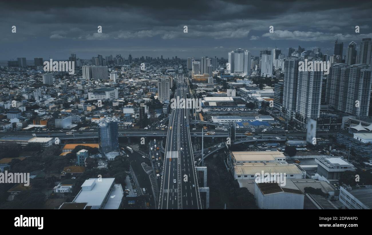 Route de circulation avec voitures et camions à l'antenne de rue urbaine. Gratte-ciels hauts, bâtiments dans le paysage urbain de la métropole philippine de Manille. Transport cinématographique de véhicules dans des tons spectaculaires Banque D'Images
