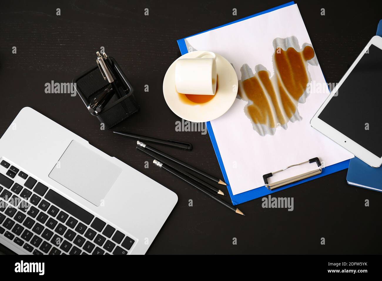 Un ordinateur portable, une tablette et une tasse de café retournée sur une table Banque D'Images Un ordinateur portable, une tablette et une tasse de café retournée sur une table Banque D'Images