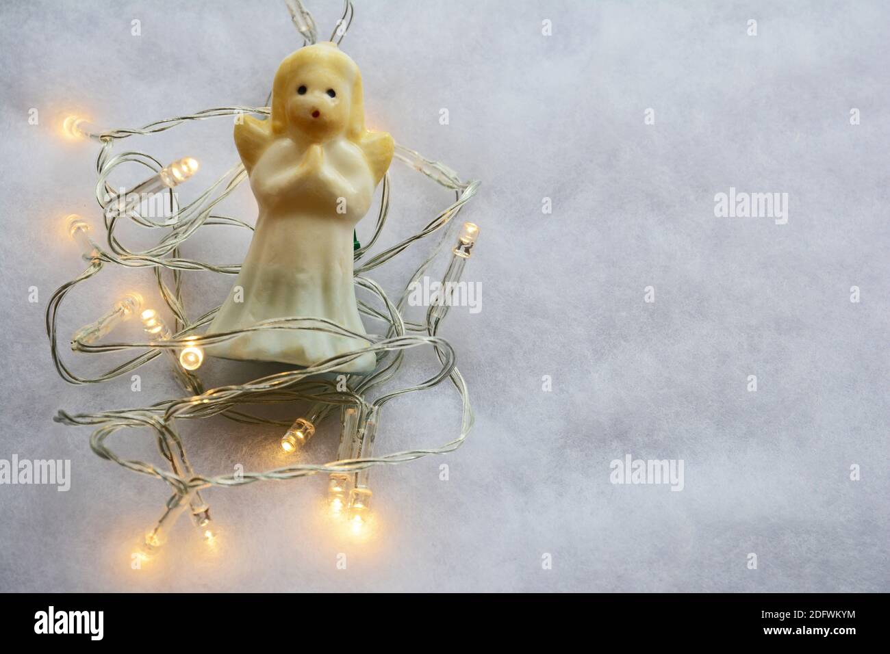 Guirlande lumineuse de Noël blanche avec un ange de prière sur fond gris avec espace pour les copies. Banque D'Images