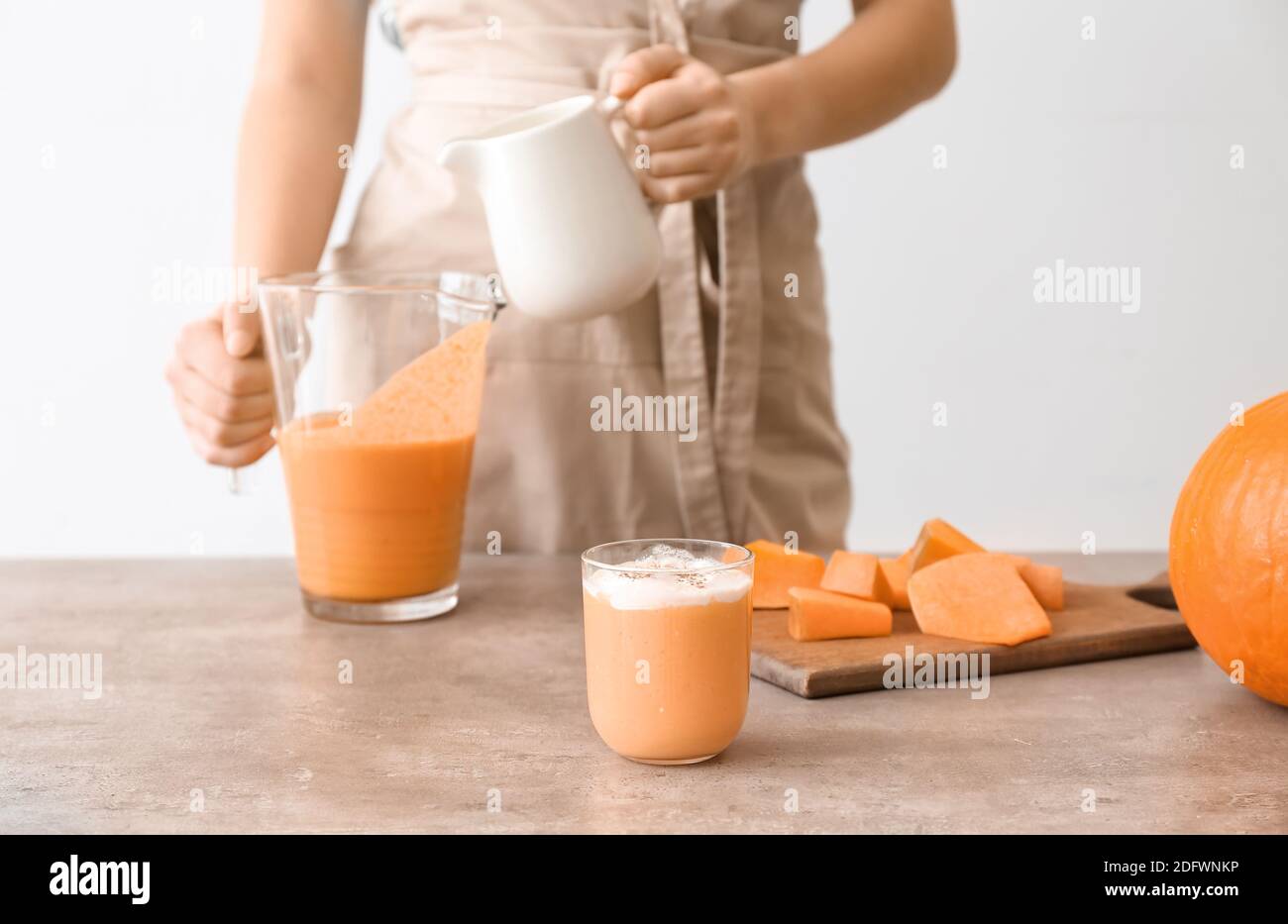 Femme préparant un délicieux smoothie à la citrouille à table Banque D'Images