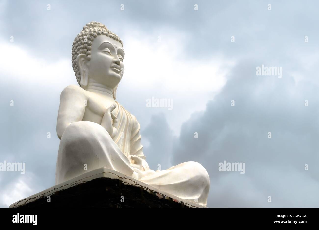 Belle photo de la sculpture de Bouddha de Seigneur en blanc, assis calme et composé, rayonnant l'énergie positive tout en donnant sermon avec fond de ciel. Banque D'Images