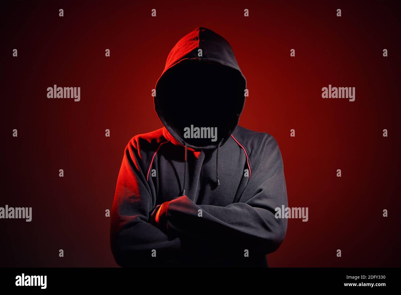 Silhouette af man sans visage dans la capuche sur fond rouge. Concept de crime anonyme Banque D'Images