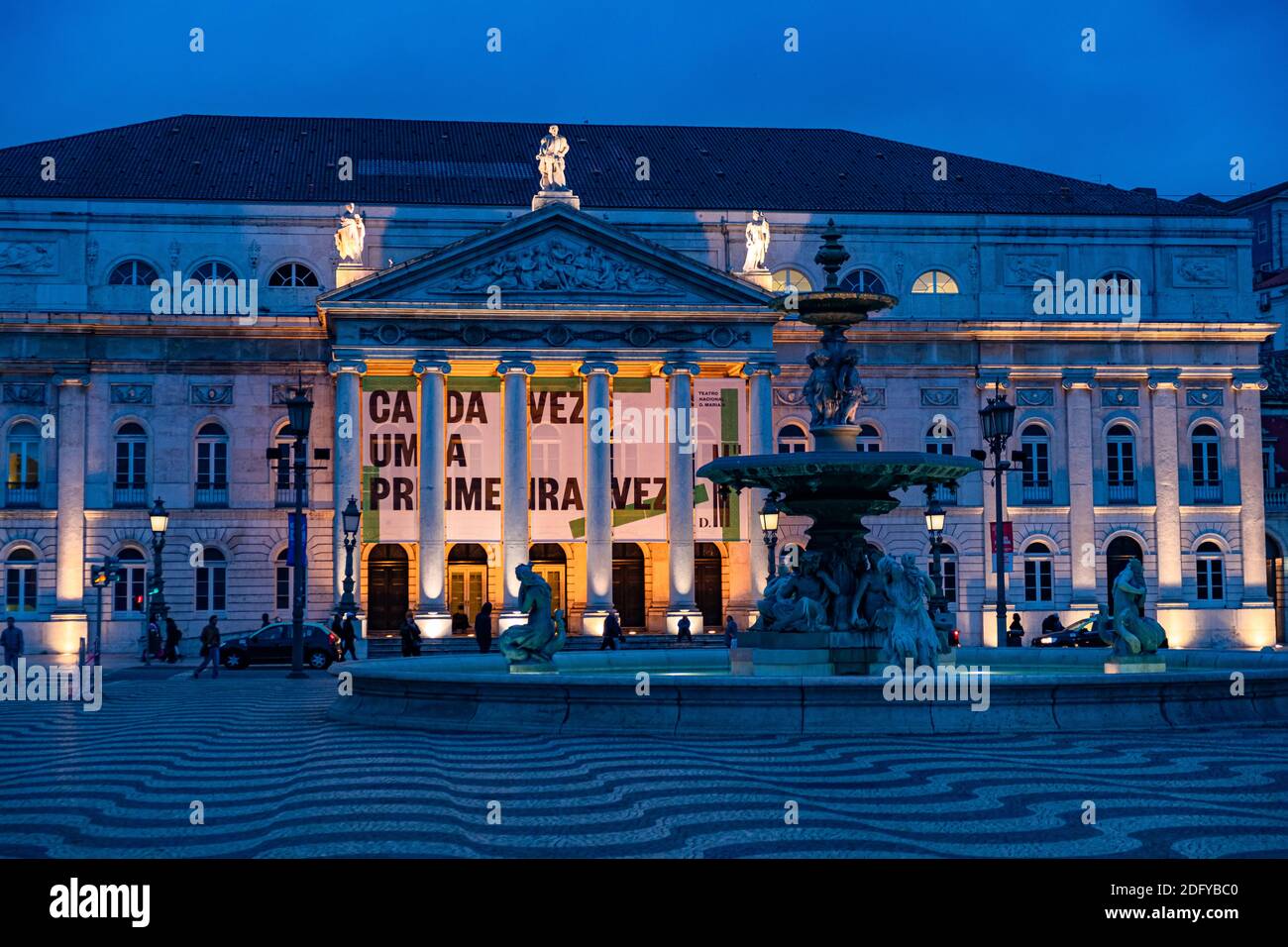 Fontaine en bronze et façade illuminée du Théâtre national de la place Rossia à Lisbonne, Portugal. Prise en soirée Banque D'Images