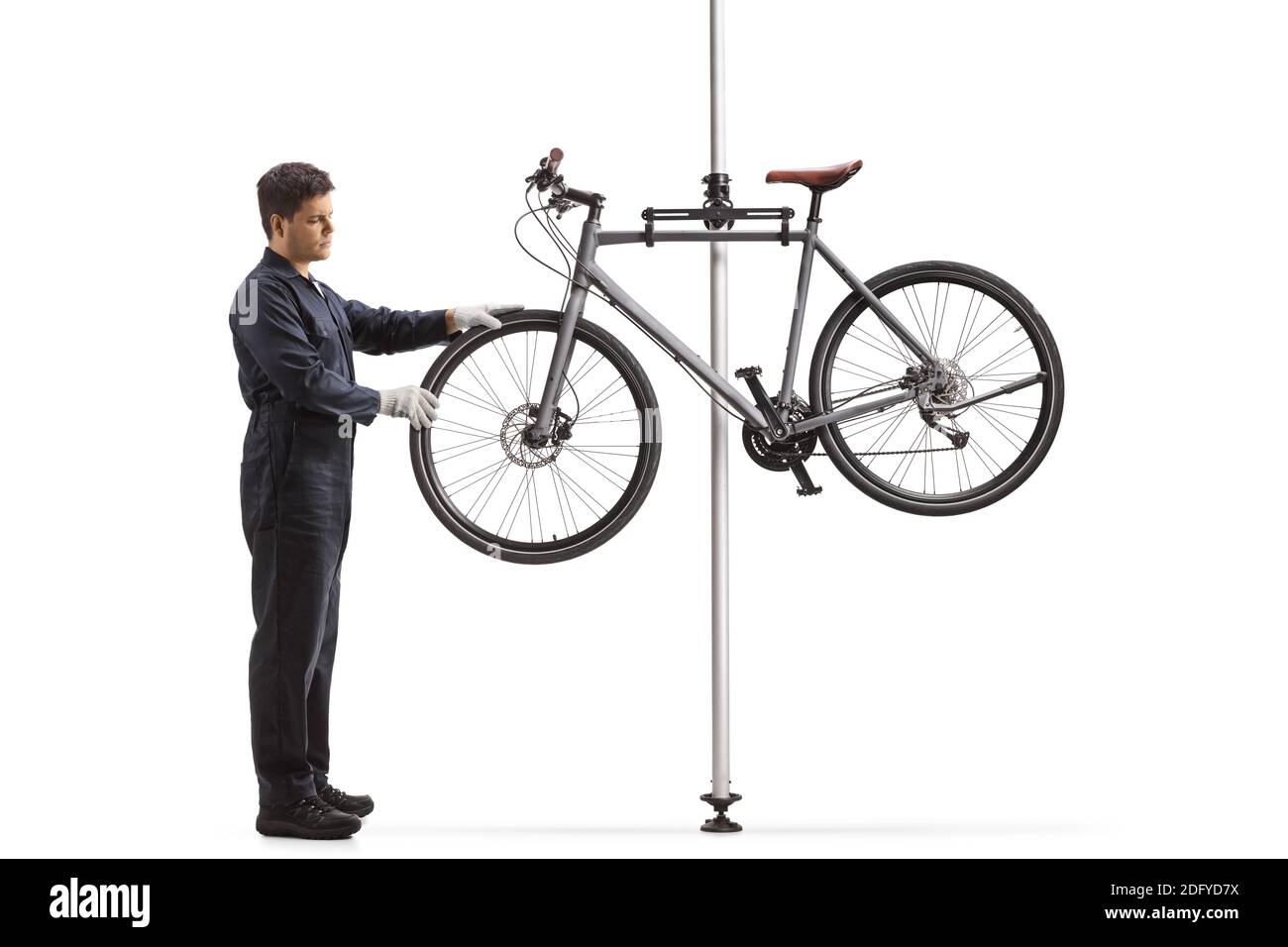 Homme en uniforme réparant un vélo suspendu sur un se tenir isolé sur fond blanc Banque D'Images
