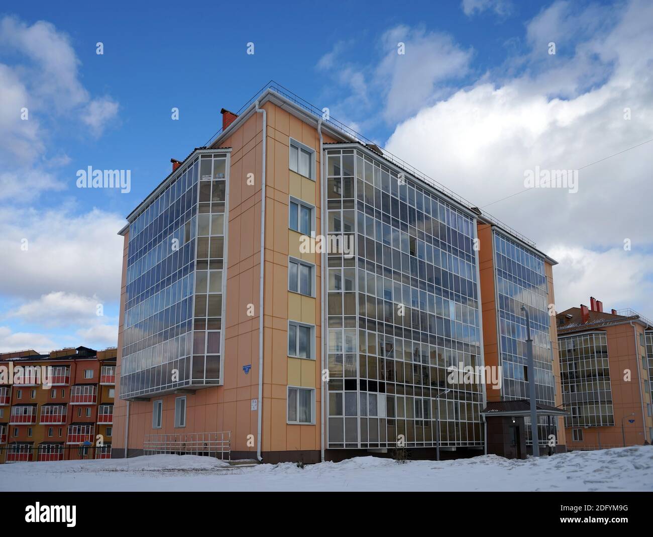 Un nouvel immeuble résidentiel en briques avec balcons vitrés se dresse au milieu de la neige dans le village de Tayozhny, dans le territoire de Krasnoyarsk. Russie. Banque D'Images