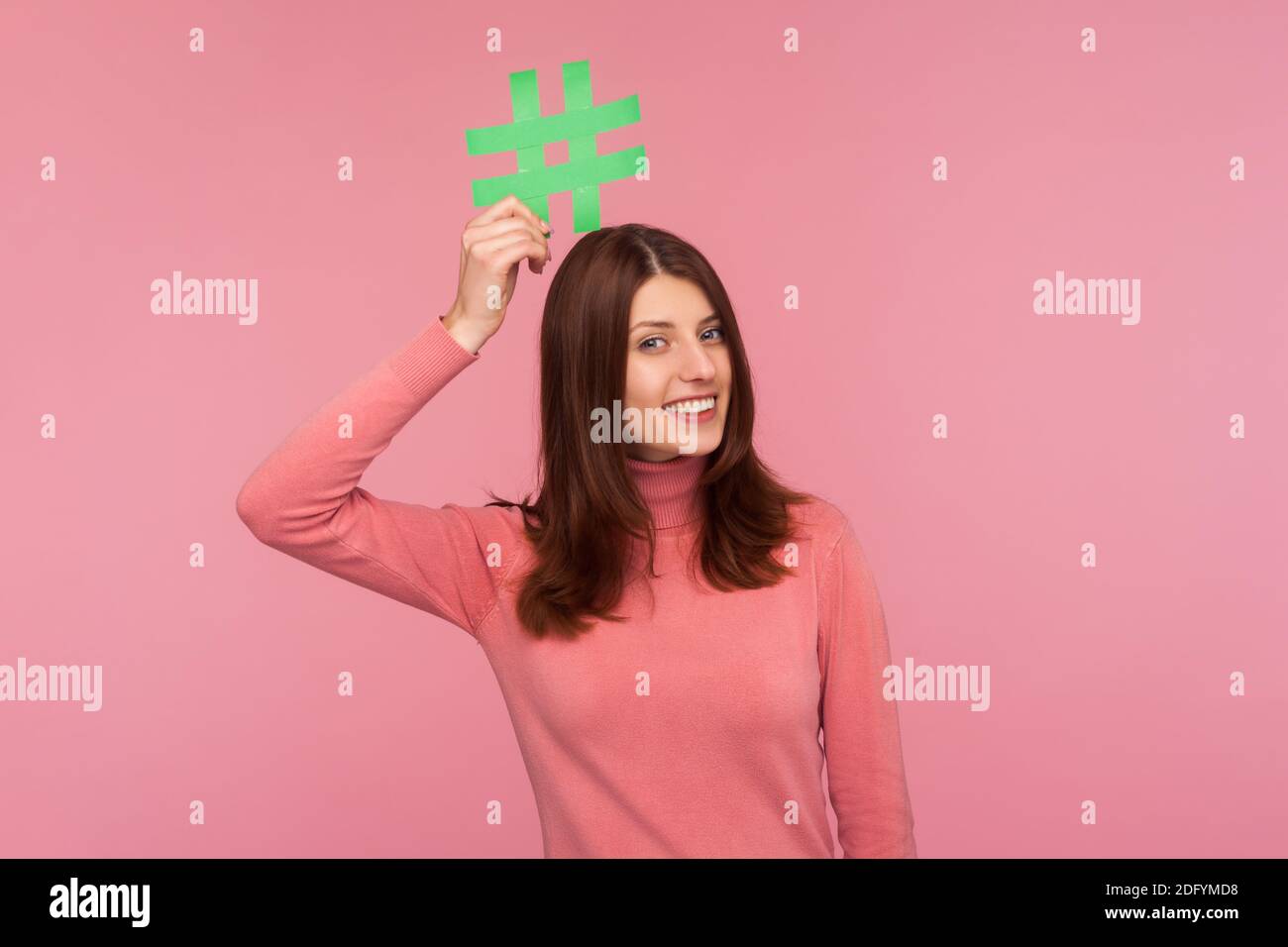 Femme souriante brune tenant le symbole jaune hashtag sur sa tête, rendant les sujets populaires, établissant des tendances sur Internet. Prise de vue en studio isolée sur pi Banque D'Images