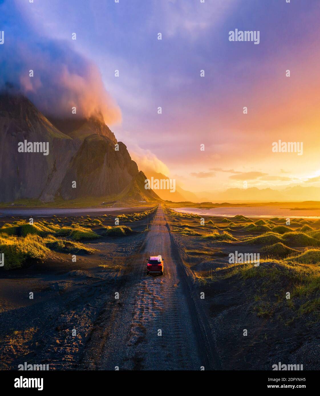 Route de gravier au coucher du soleil avec la montagne de Vestrahorn et une voiture de conduite, Islande Banque D'Images