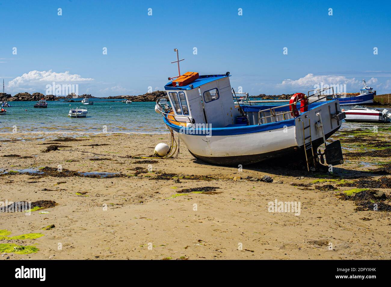 Bateau toronné bateau de pêche sur une plage en Bretagne, France. Paysage breton en été. Un bateau de pêche toronné sur le sable à marée basse. Banque D'Images
