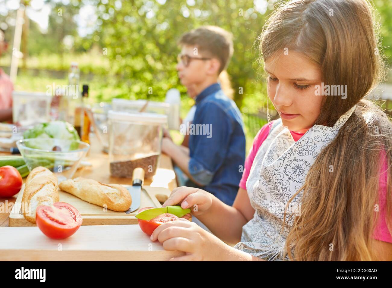 Fille dans camp d'été végétarien régime cuisine cours coupes a tomate Banque D'Images