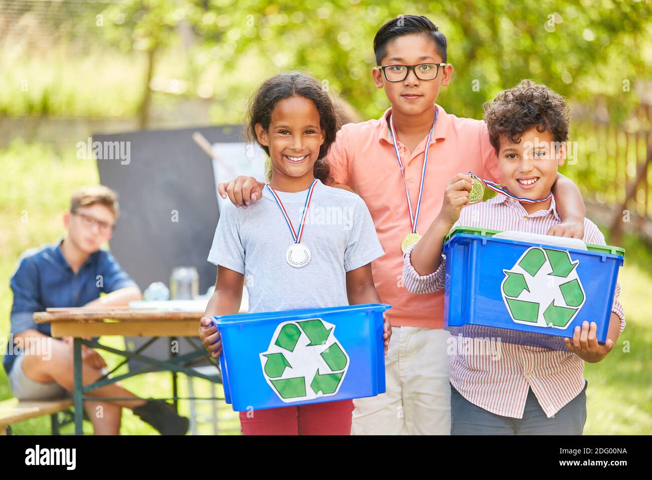 Trois enfants avec des médailles comme écologistes volontaires dans un recyclage projet Banque D'Images