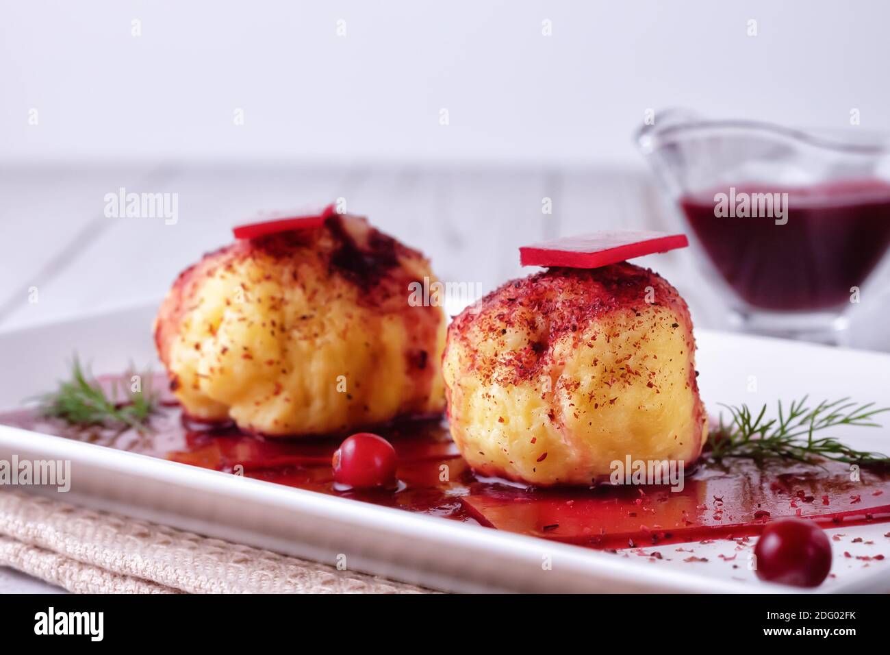 Boulettes de pommes de terre suédoises fraîchement cuites avec sauce aux canneberges sur fond clair. Banque D'Images