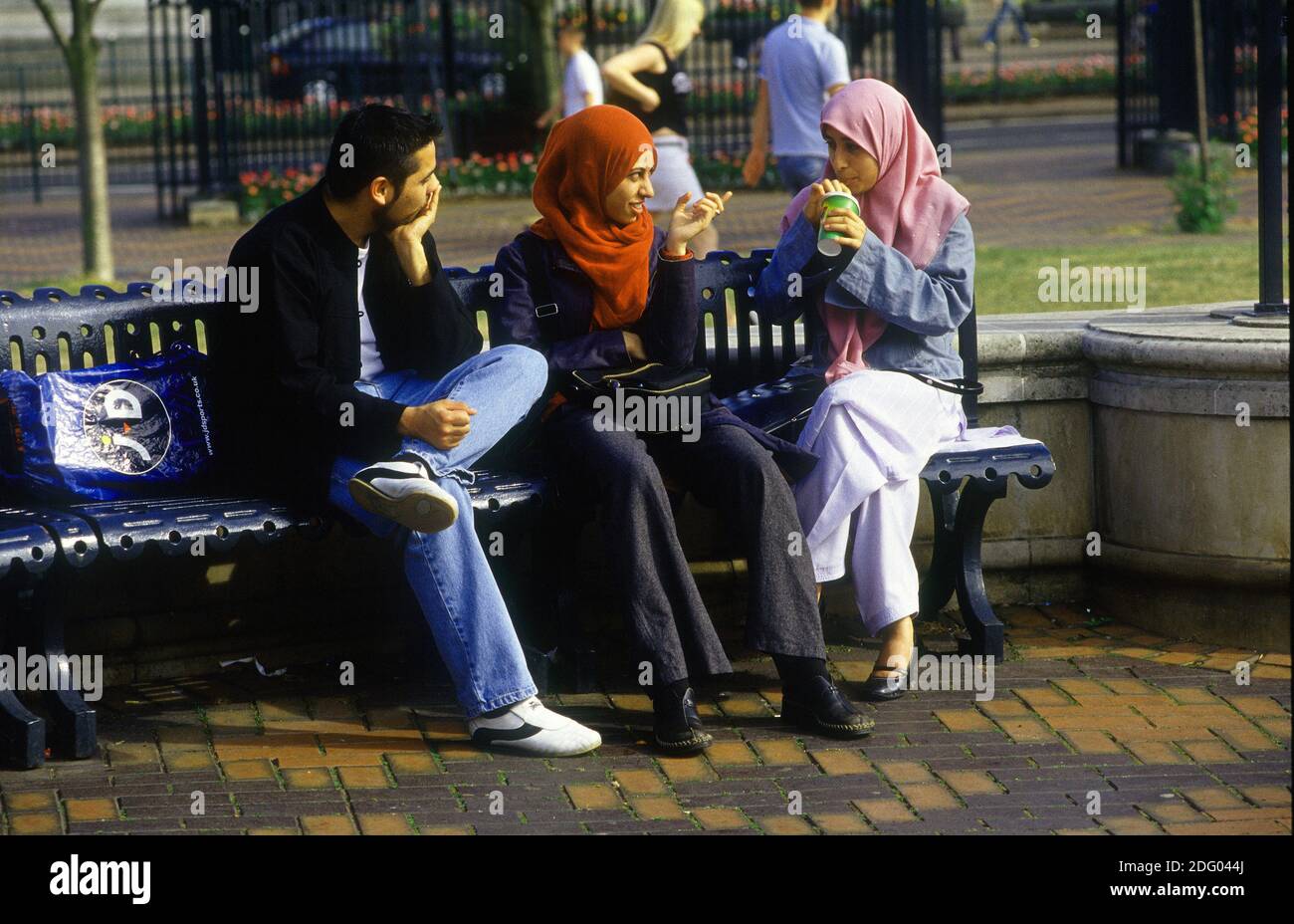 Les filles musulmanes et leur compagnon masculin s'attchat ensemble sur un Banc à la place du Centenaire de Birmingham Banque D'Images