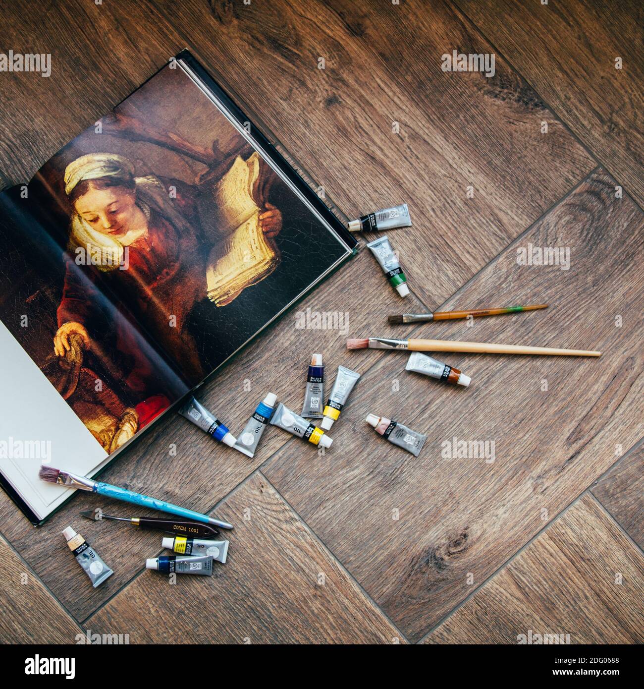 Les peintures à l'huile, les pinceaux et un livre sur les artistes se trouvent sur la tuile, l'endroit pour le texte Banque D'Images