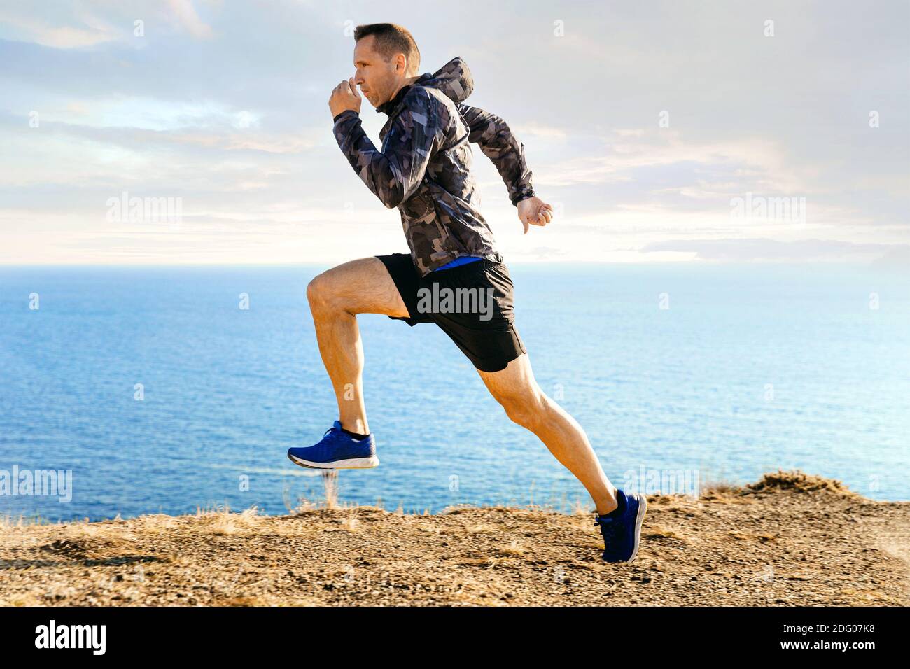 coureur masculin dans coupe-vent courant en arrière-plan dans le ciel et la mer Banque D'Images