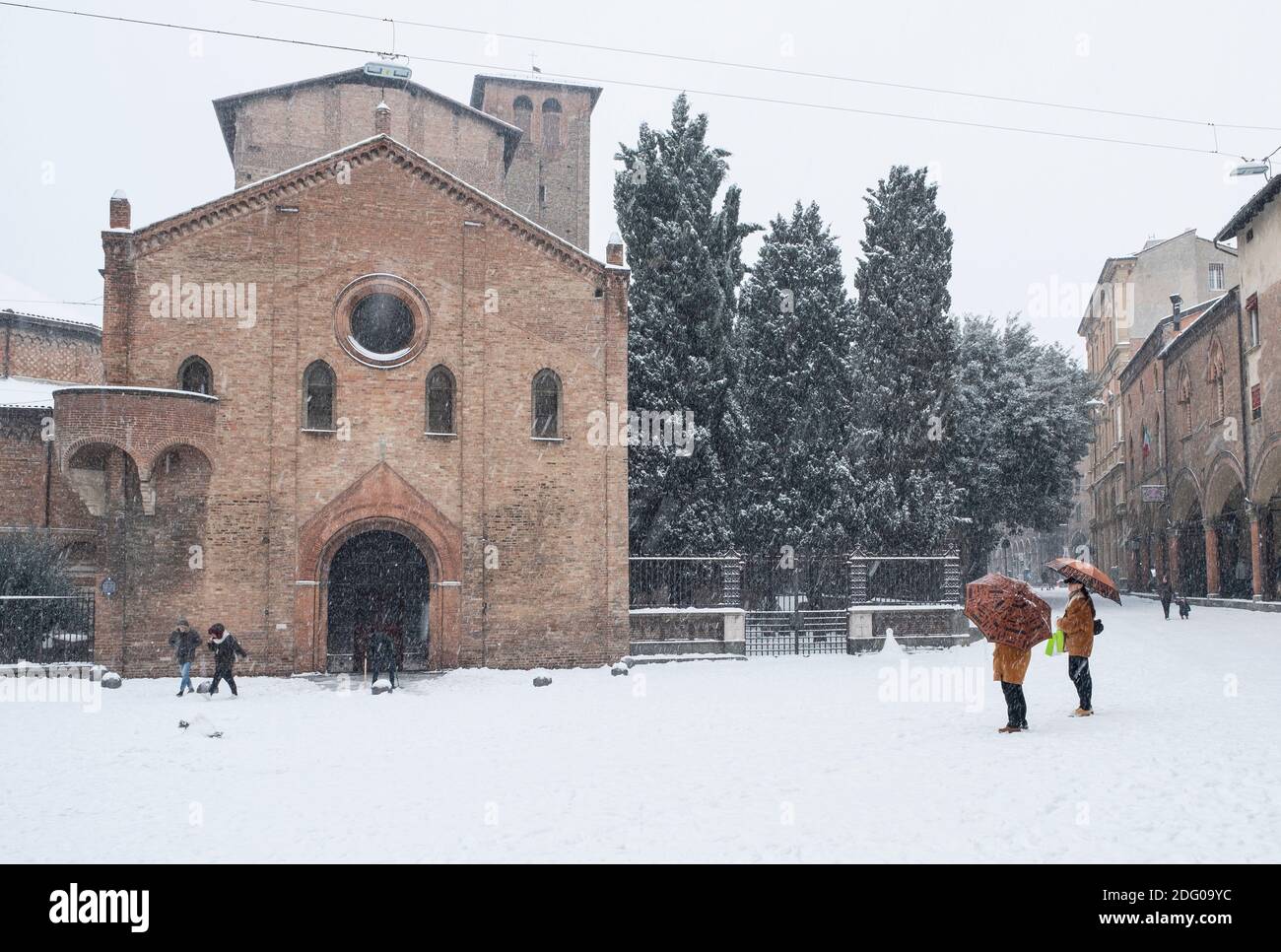 Deux femmes sous des parasols dans la neige tombant à l'extérieur de la basilique de Santo Stefano, Bologne, Italie. Banque D'Images