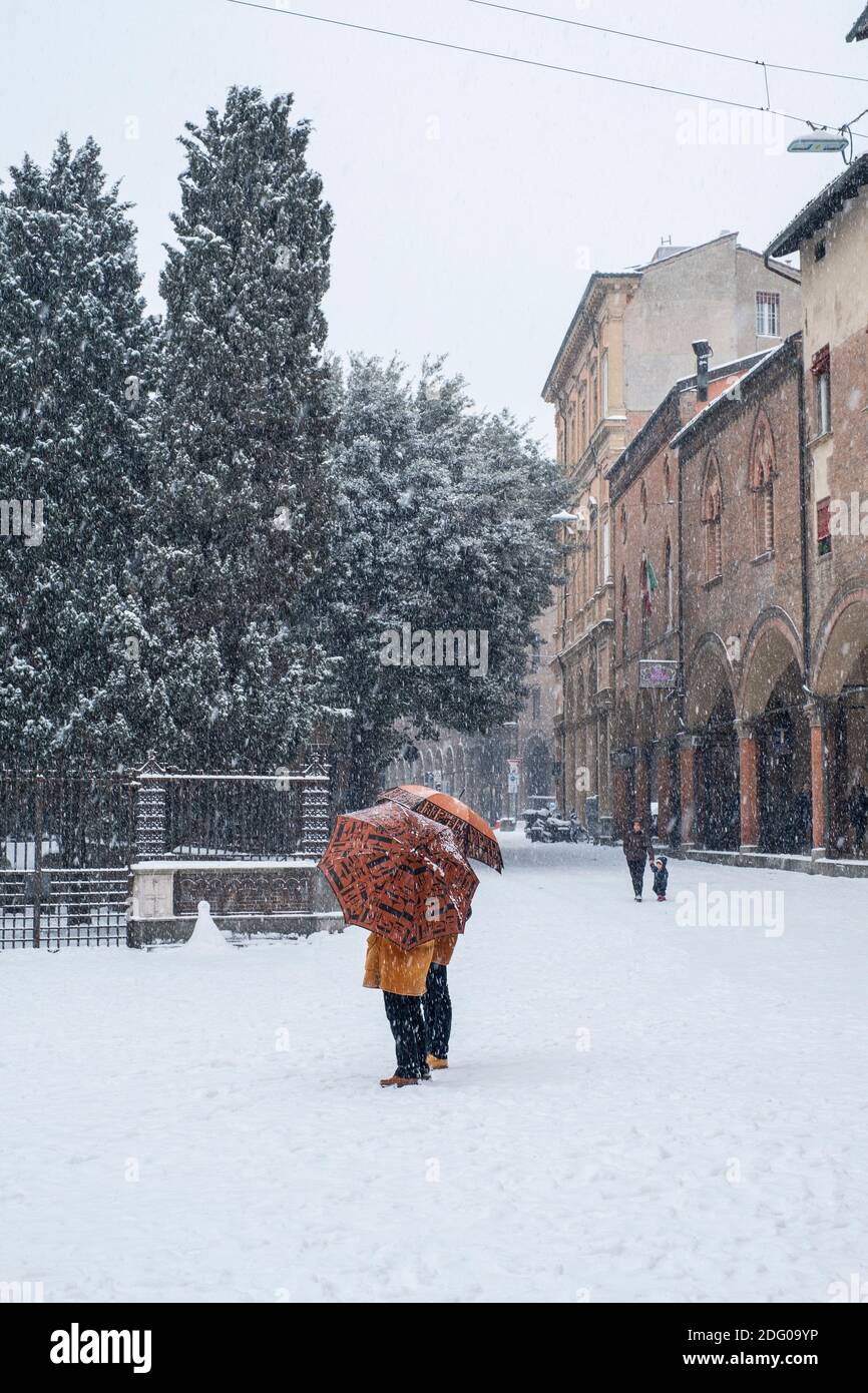 Deux femmes sous des parasols dans la neige tombant sur la Piazza di Santo Stefano, Bologne, Italie. Banque D'Images