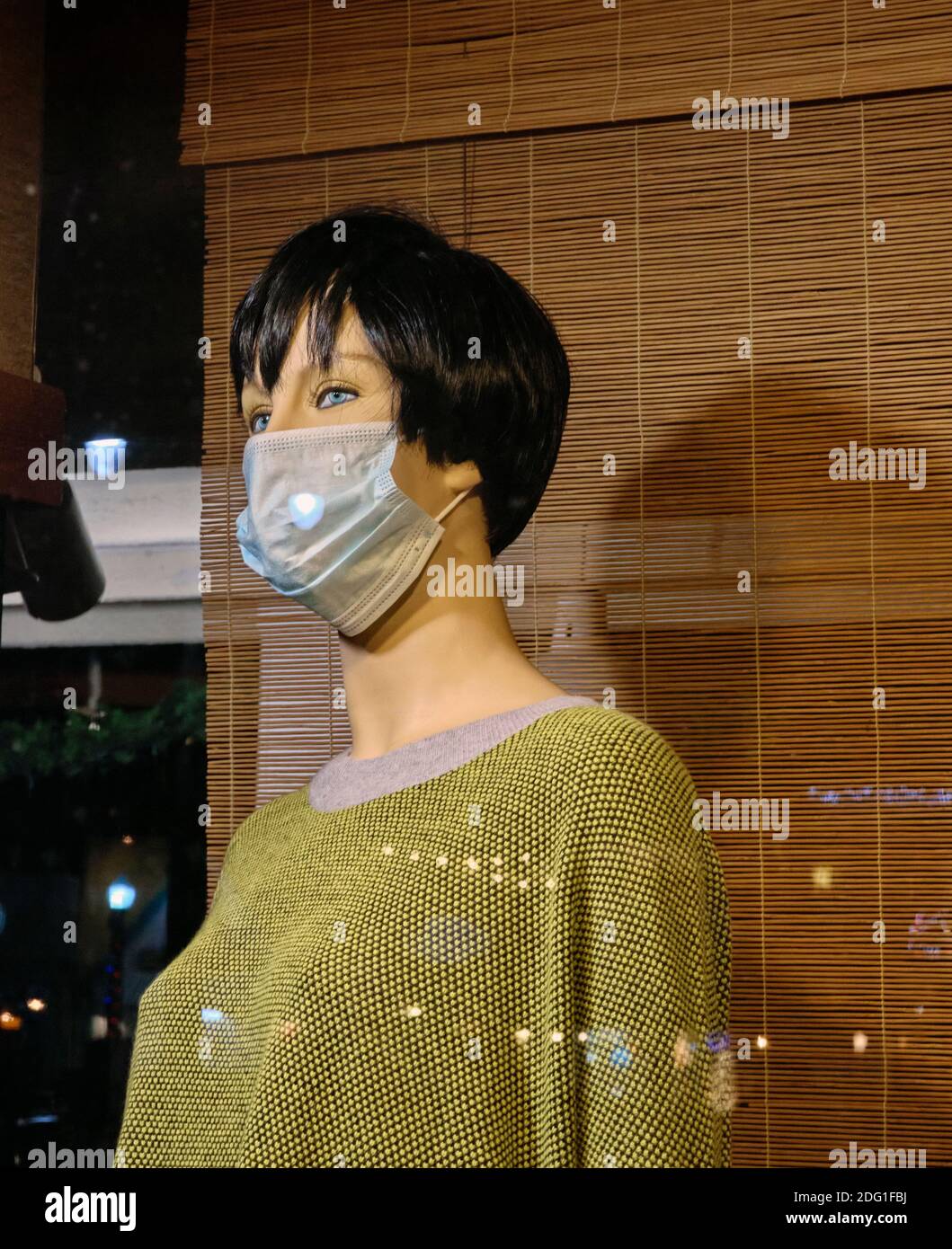 Un mannequin de la fenêtre du magasin porte un chemisier vert et un masque facial pendant la pandémie du coronavirus COVID-19 de 2020. Banque D'Images