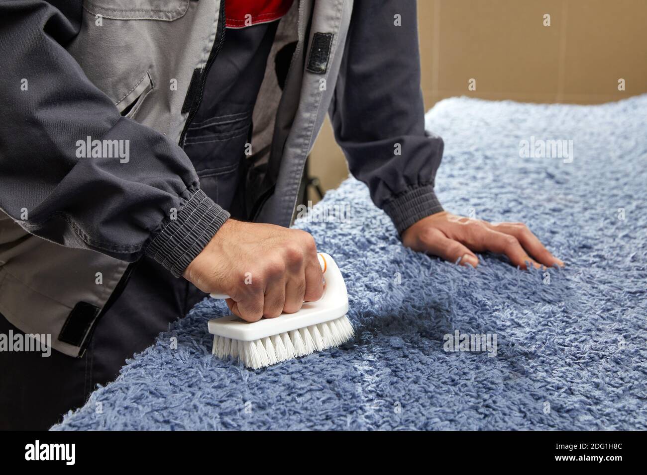 Homme pulvérisant du détergent sur le tapis gris pour enlever la tache dans  service de nettoyage professionnel Photo Stock - Alamy