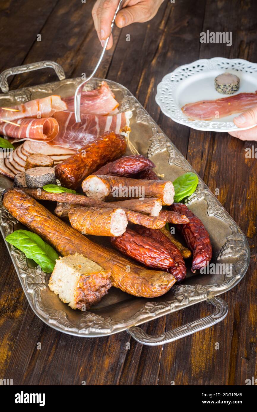 Divers types de charcuterie appétissante sur un élégant plateau arrière-plan, ancienne table en bois Banque D'Images