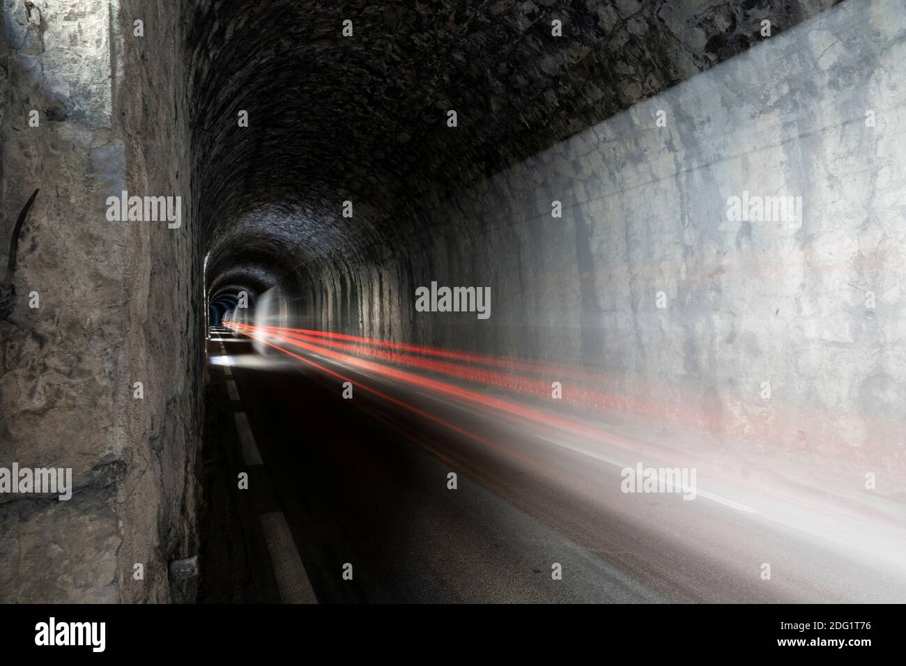 Longue exposition, piste lumineuse de voiture dans un tunnel de montagne sombre Banque D'Images