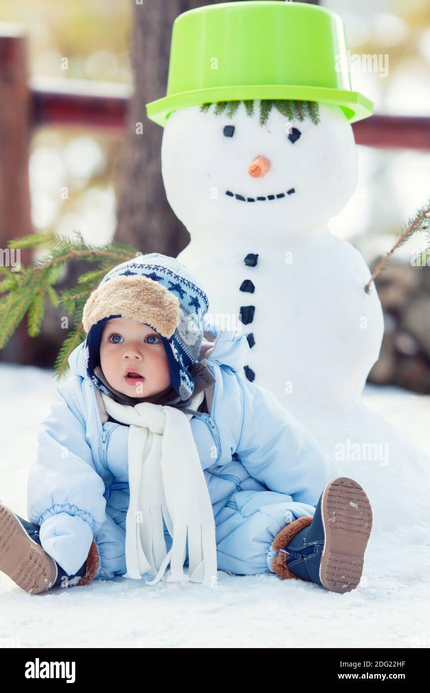 Beau bébé garçon assis sur la neige et posant. Saison d'hiver. Banque D'Images