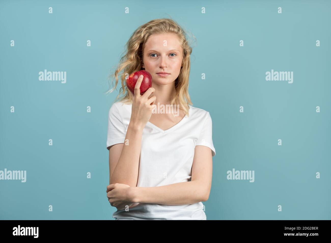 Belle jeune femme avec une peau propre et fraîche sans maquillage avec de longs cheveux bouclés tenant la pomme Banque D'Images