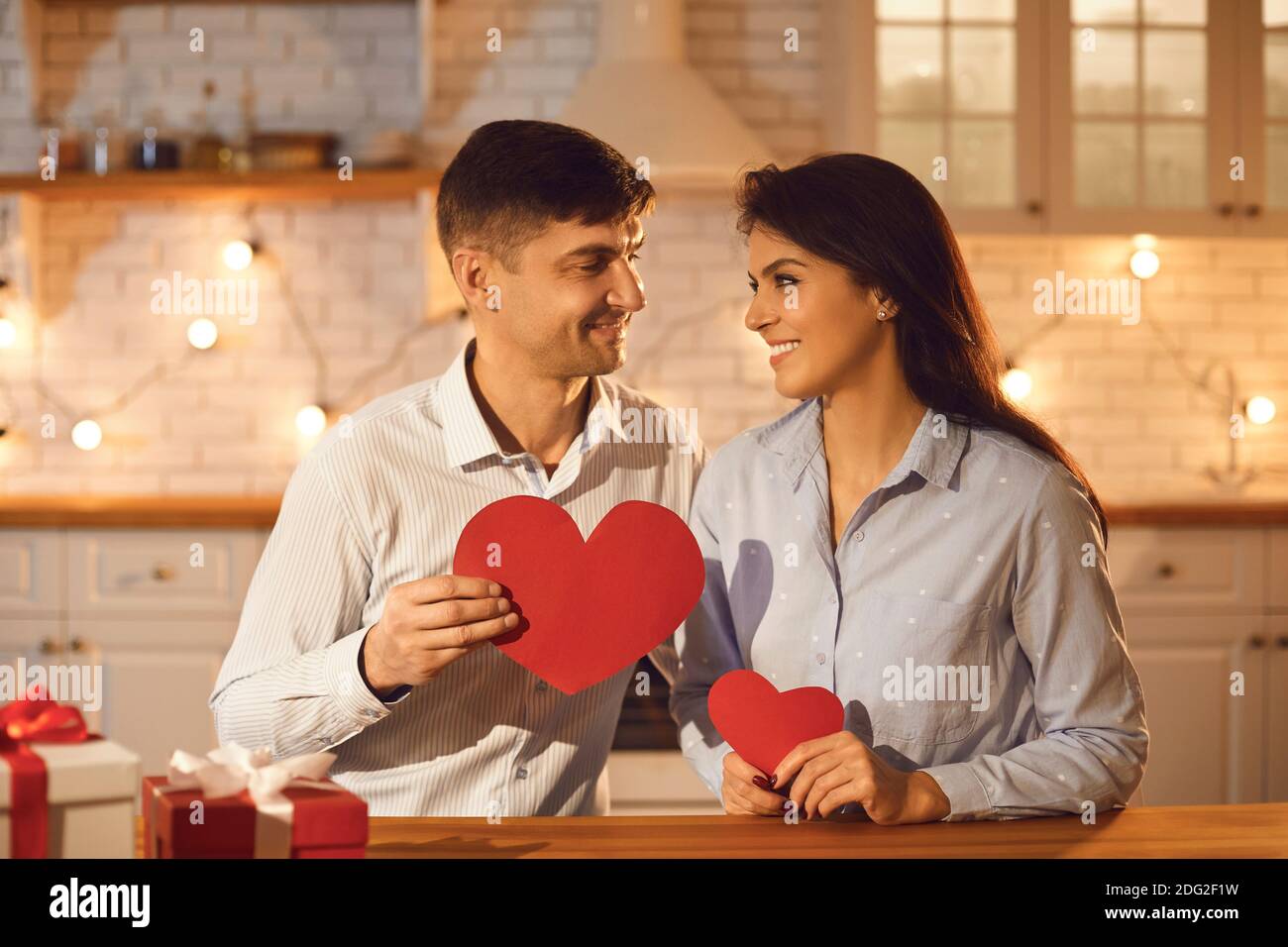 Heureux jeunes amoureux de couple avec coeur rouge dans les mains regardant Les uns aux autres pendant la fête de la Saint-Valentin Banque D'Images