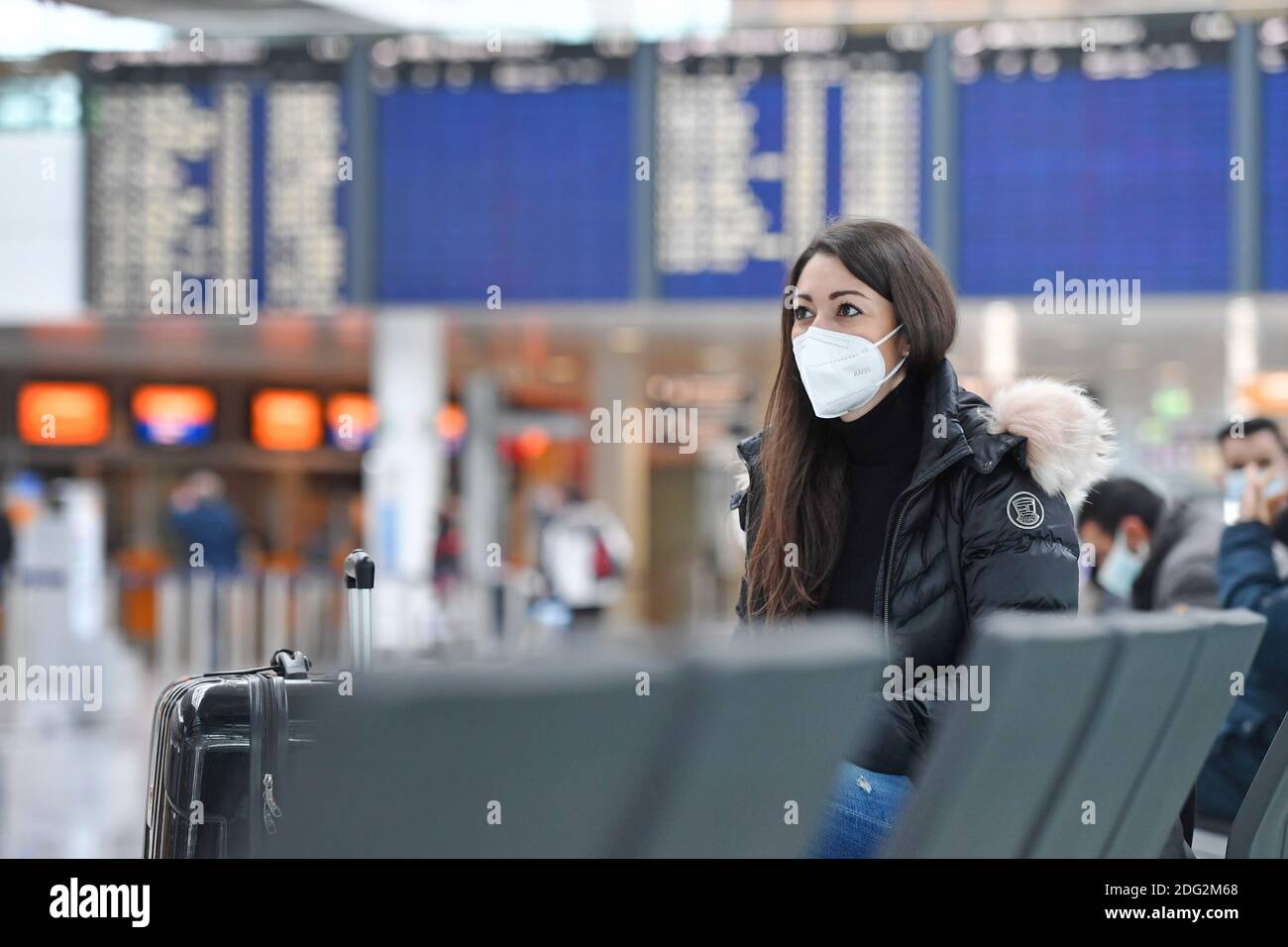 Voyages à thème en période de pandémie de corona. Jeune femme avec masque, masque à l'aéroport de Munich le 6 décembre 2020. Assis dans le terminal, hall des départs, en attente du départ. MODÈLE DISPONIBLE ! | utilisation dans le monde entier Banque D'Images