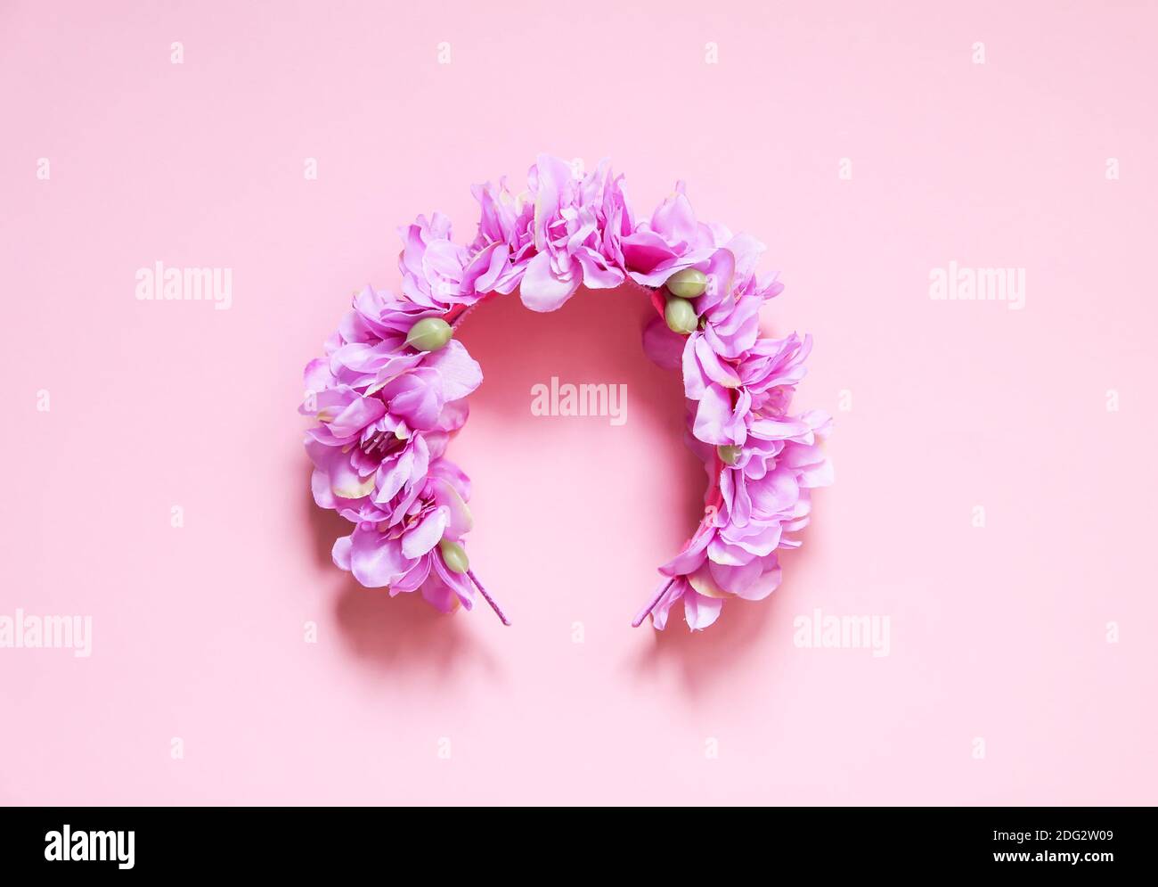 Couronne décorative artificielle de fleurs violettes sur fond rose avec espace pour les copies. Banque D'Images