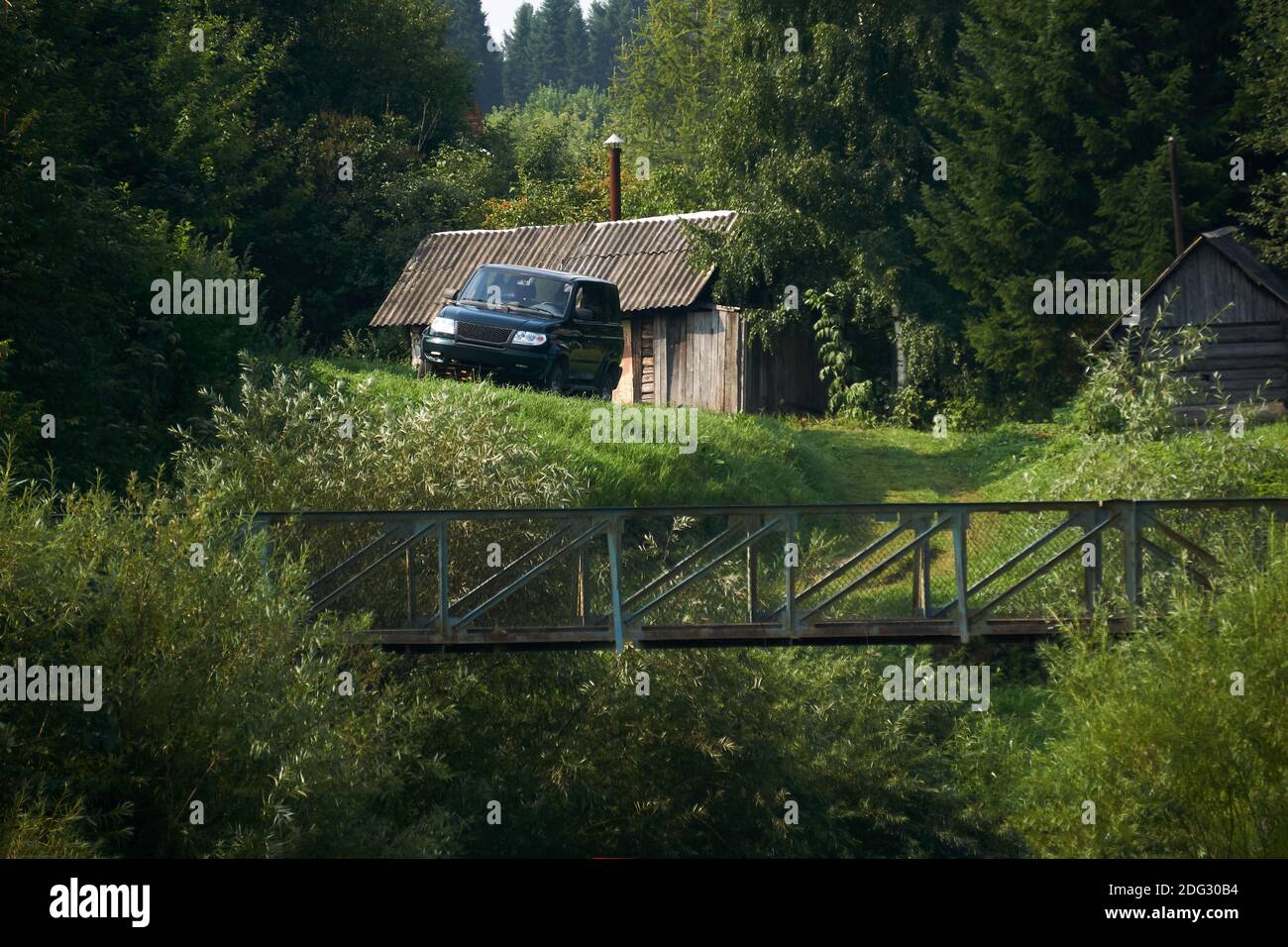 paysage rural, une ferme isolée dans la forêt - une cabane en rondins, une bathhouse et un véhicule tout-terrain sur le bord d'un ravin avec un pont Banque D'Images