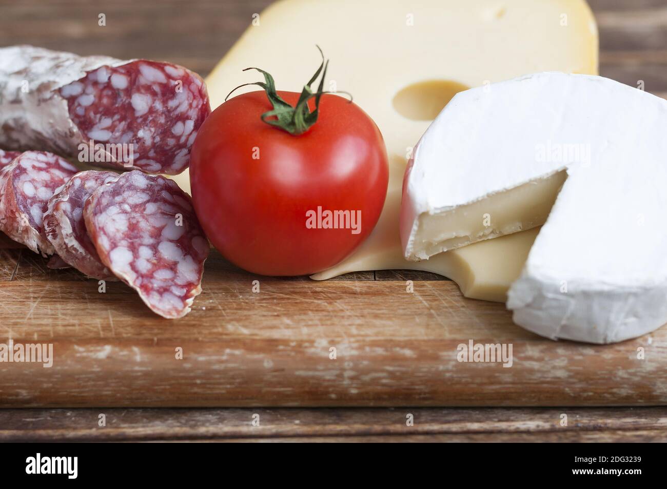 Délicatesse méditerranéenne, salami et fromage avec tomates rouges comme arrière-plans alimentaires. Banque D'Images