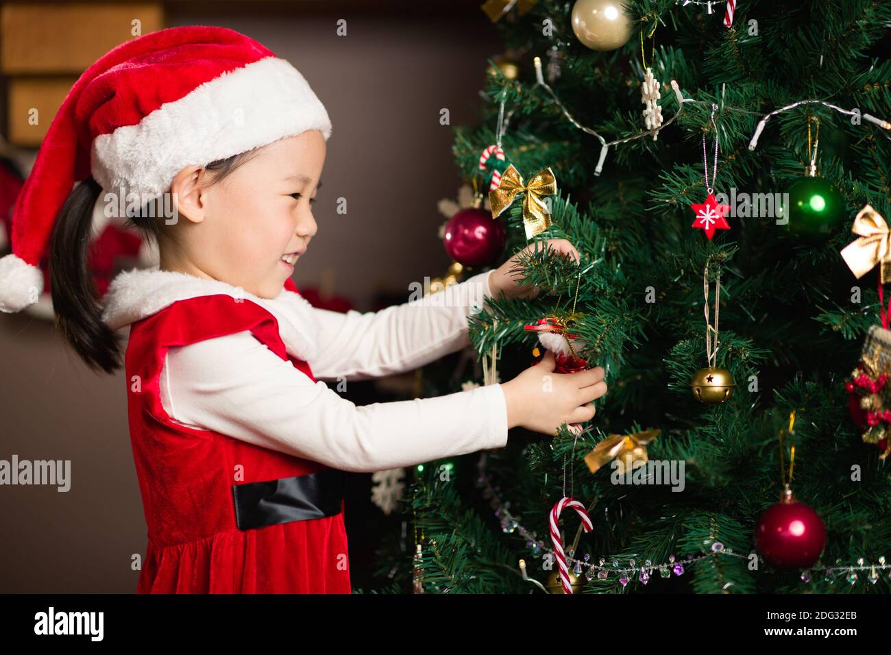 Jeune fille décorant l'arbre de Noël à la maison Banque D'Images