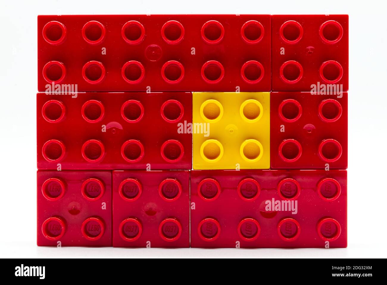Bloc de construction Lego en plastique jaune entouré de rouges. Concept d'isolement et de diversité Banque D'Images