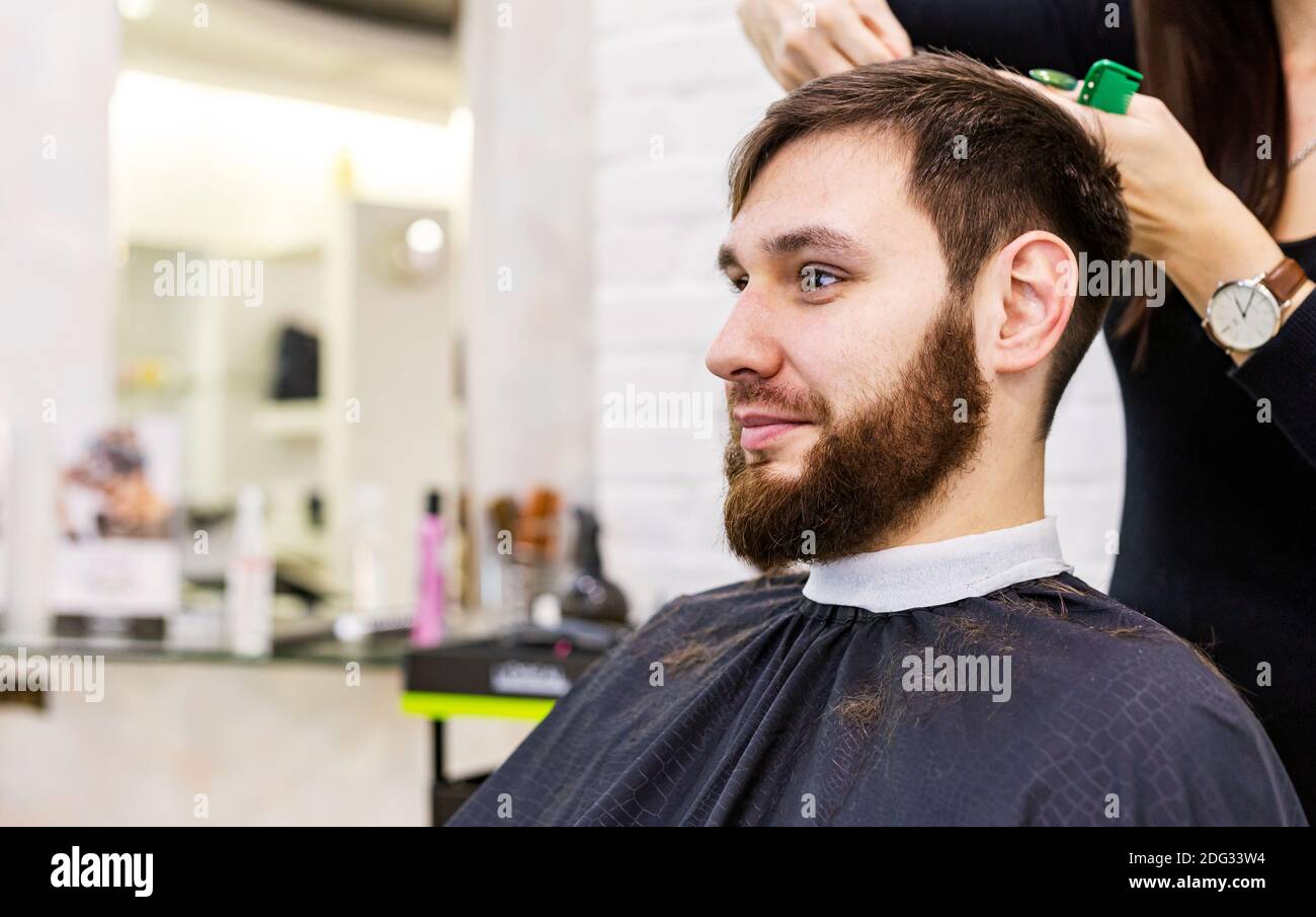 Coiffeur Faisant La Coupe De Cheveux De La Barbe à L'aide D'un Peigne Et De  Ciseaux Pour Un Jeune Homme Séduisant Dans Un Salon De Coiffure Pour Hommes