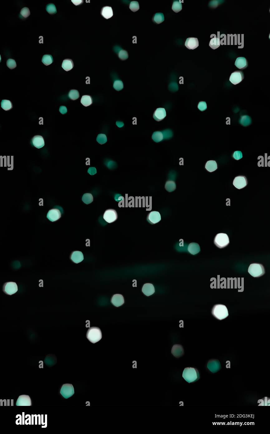 Vert pâle s'allume sur un arrière-plan flou. Points laser sur fond noir pour célébrer les événements et les cartes de vœux Banque D'Images