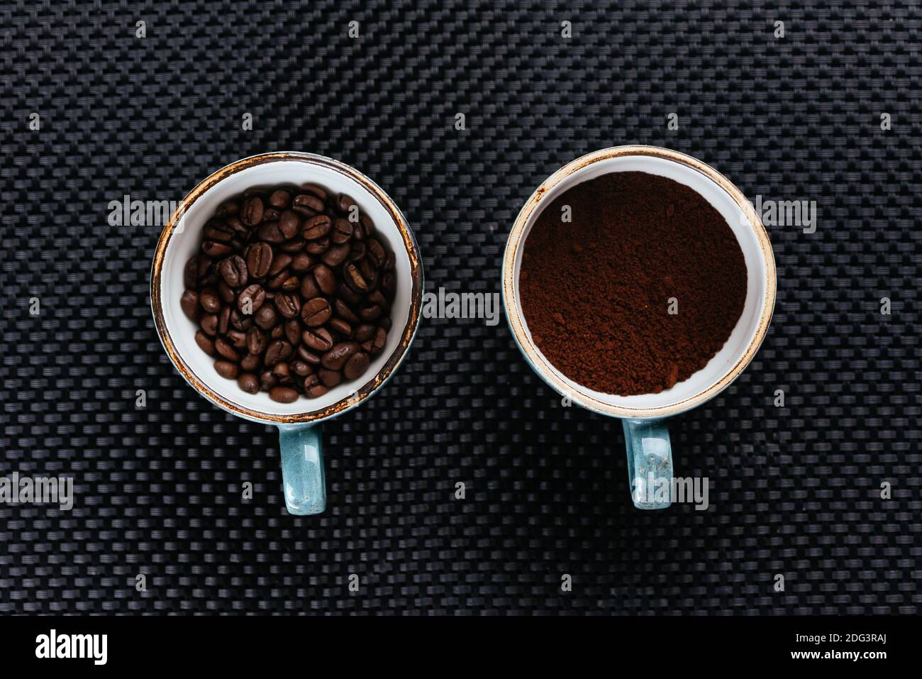 café moulu et grain en tasses sur fond noir Banque D'Images