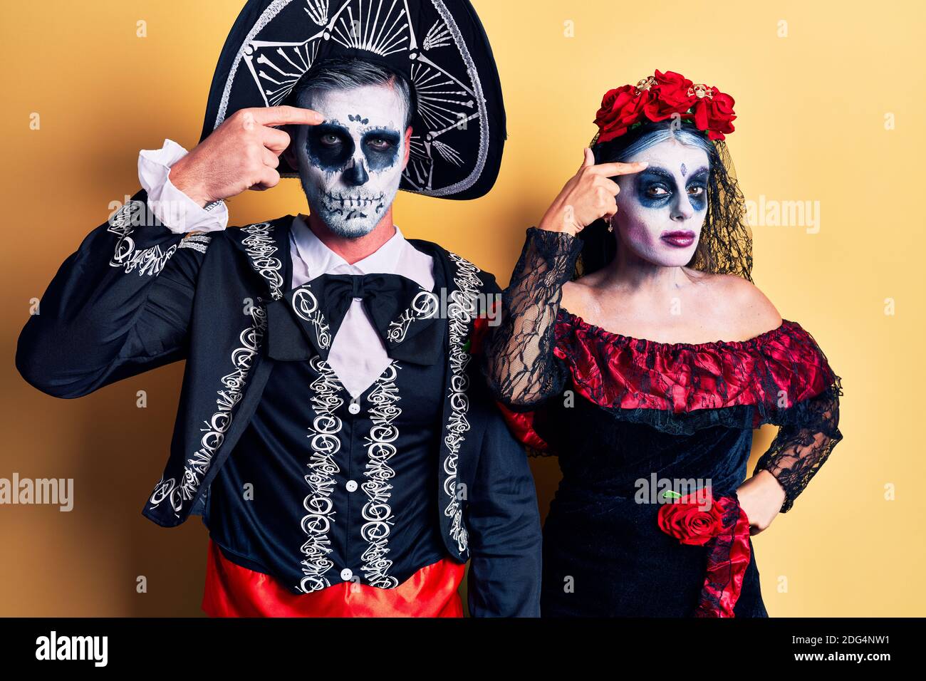 Déguisement Dia De Los Muertos Couple Jeune couple portant le jour mexicain du costume mort sur jaune pointant  malheureux à pipple sur le front, infection laid de la tête noire. Acné et  la peau pr Photo Stock -