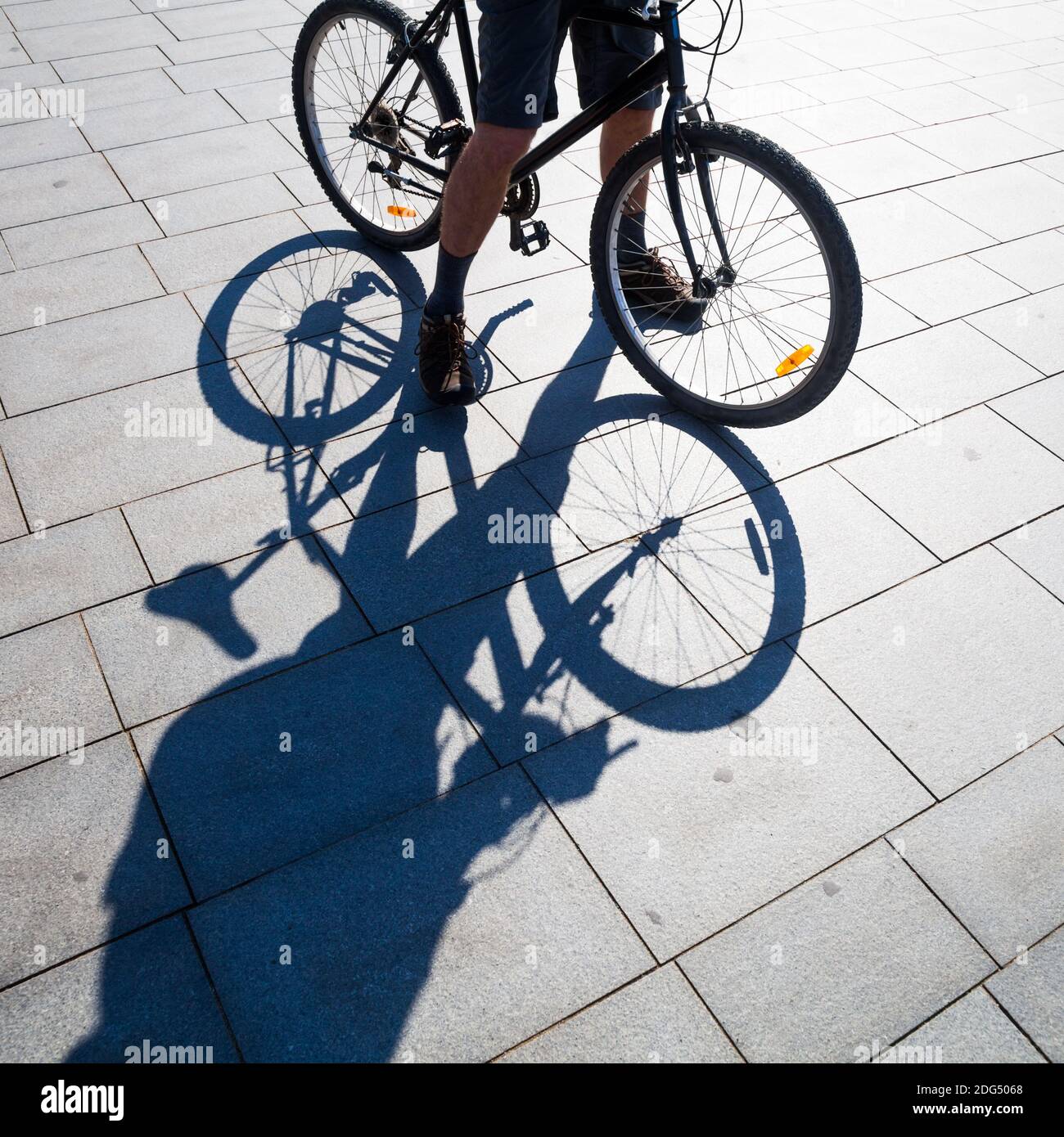 Homme avec vélo faisant de l'ombre sur la chaussée Banque D'Images Homme avec vélo faisant de l'ombre sur la chaussée Banque D'Images