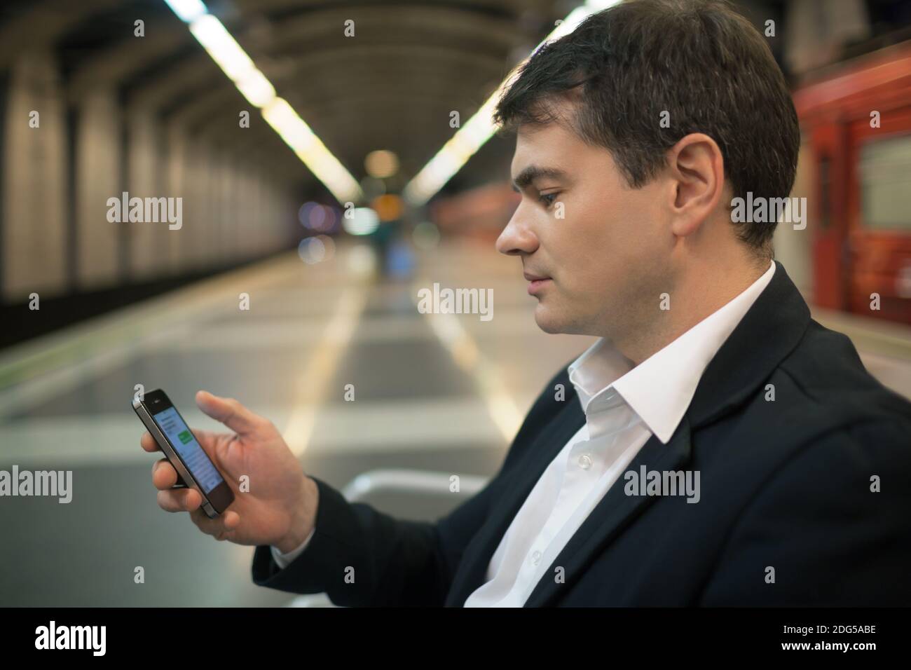 Jeune homme lisant des sms sur un smartphone en sous-sol Banque D'Images